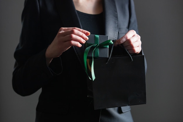 Frau in schwarzer Jacke hält Geschenkbox