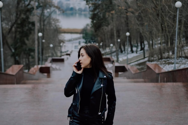 Frau in schwarzer Kleidung, die auf dem Handy spricht