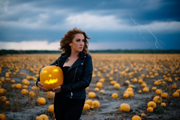 Foto frau in schwarzer kleidung hält kürbis in ihren händen, halloween-konzept