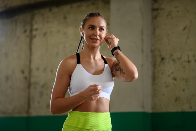 Frau in Sportkleidung, die sich vor dem Training Airpods in die Ohren steckt