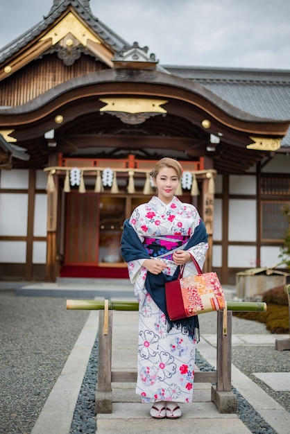 Frau in traditioneller japanischer Tracht zu Fuß unter Tori-Tore am Fushimi-Inari-Schrein, Kyoto Japan