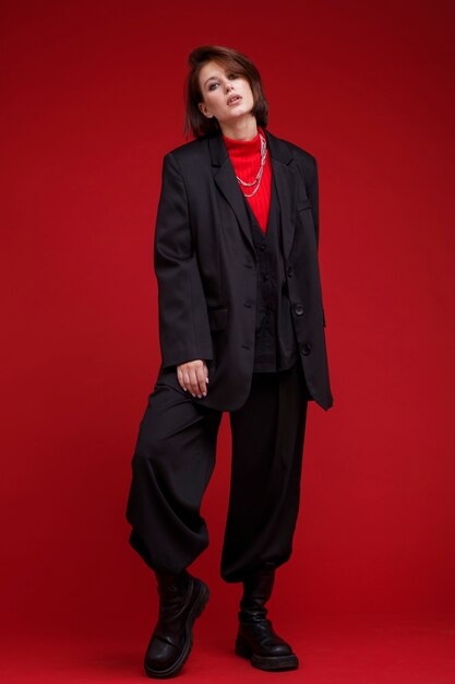 Frau in übergroßer schwarzer Anzughose auf rotem Hintergrund Bob-Haarschnitt Studio Shot Rebel classic