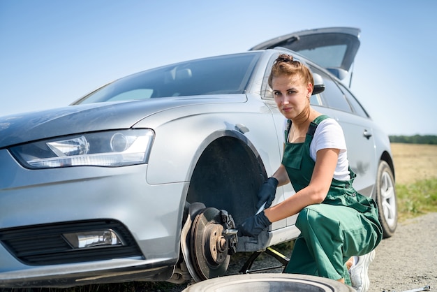 Frau in Uniform, die für Autobremsenwartung arbeitet. Autoreparatur. Sicherheitsarbeit