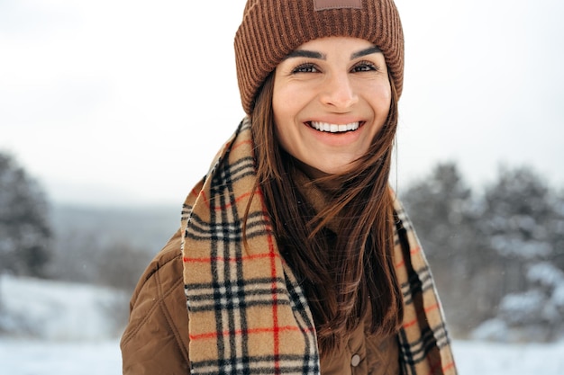 Frau in warmer Winterjacke, die im verschneiten Winterwald spazieren geht