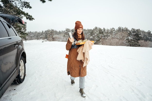 Frau in warmer Winterjacke, die im verschneiten Winterwald spazieren geht