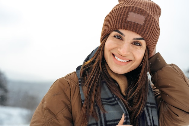 Frau in warmer Winterjacke, die im verschneiten Winterwald spazieren geht