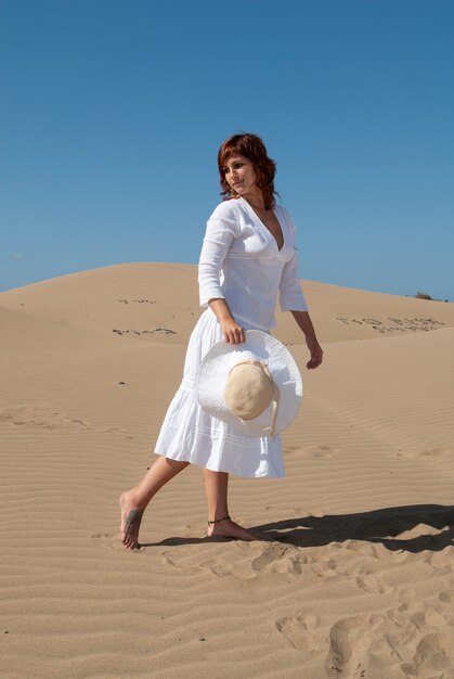 Frau in Weiß, die an einem sonnigen Frühlings- oder Sommertag die Sanddünen genießt