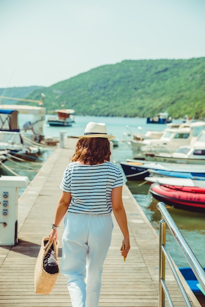 Frau in weißer Mode Luxusansicht zu Fuß durch Dockboote im Hintergrund