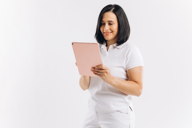 Frau in weißer Uniform hält ein Tablet auf weißem Hintergrund
