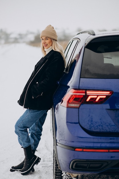 Frau in Winterkleidung, die an ihrem Auto steht