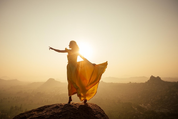 Frau ingelbes Seidenkleid mit langem Zug in den MAatanga-Hügeln in Hampi, Karnataka, Indien