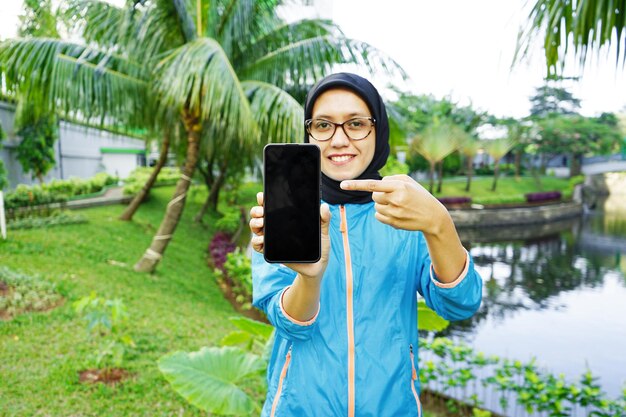 Foto frau islamisches sporttraining hijub asien, schöne frau hält telefon, mockup-handy