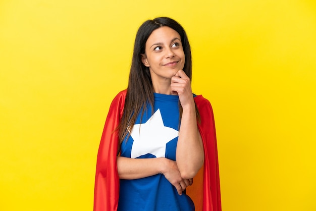 Frau isoliert auf gelbem Hintergrund in Superheldenkostüm und Denken