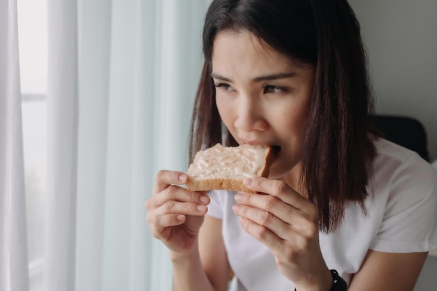 Frau isst Brot mit gesüßter Kondensmilch als einfaches Frühstück