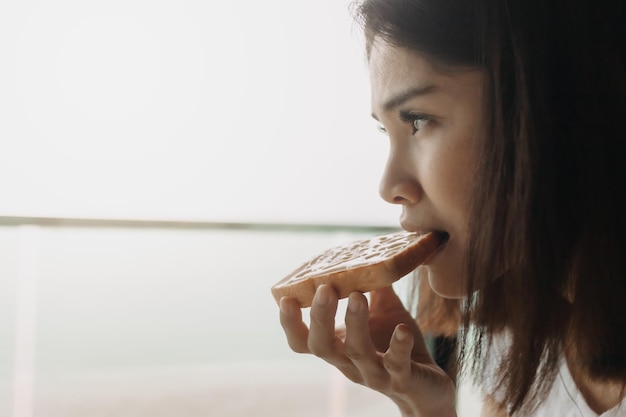 Frau isst Brot mit gesüßter Kondensmilch als einfaches Frühstück