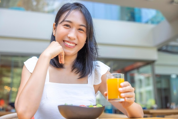 Frau isst Frühstücksfrüchte wie Wassermelone, Papaya, Melone, Passionsfrucht, Orangensaft und Kaffee