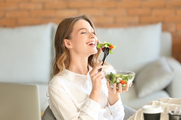 Frau isst gesunden gemüsesalat im büro eating