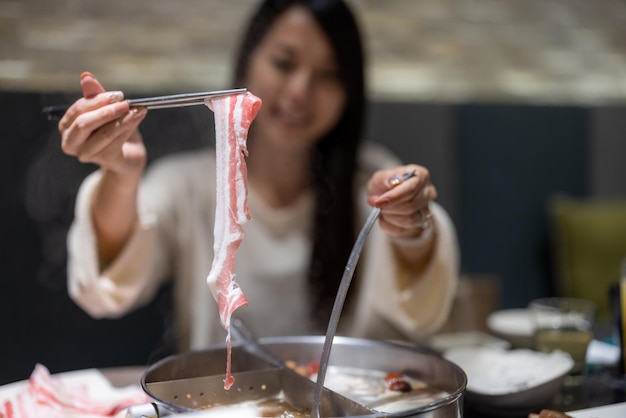 Frau isst heißen Topf im Restaurant