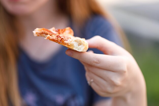 Frau isst leckere Pizza im Freien im Straßencafé Fast Food zum Mitnehmen an sonnigen Tagen