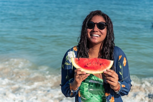 Frau isst Wassermelone am Strand