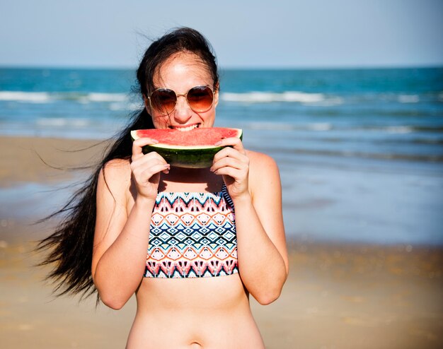 Frau isst Wassermelone am Strand