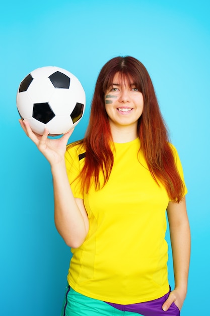 Frau ist Fußballfan im gelben T-Shirt mit Fußball auf blauem Hintergrund