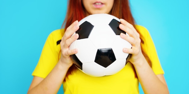 Frau ist Fußballfan im gelben T-Shirt mit Fußball auf blauem Hintergrund