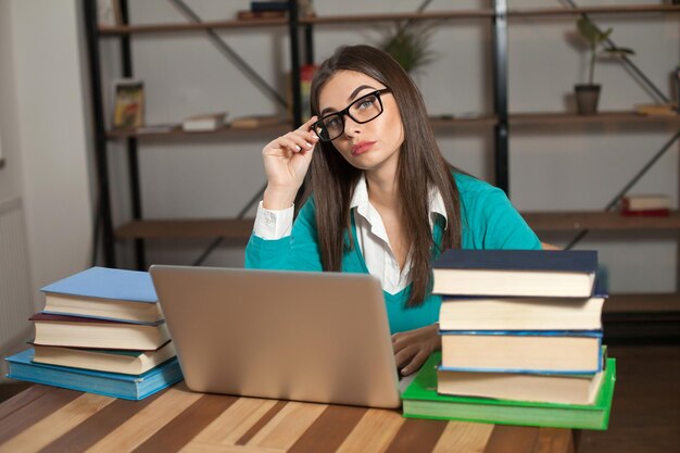 Frau ist müde Sie arbeitet mit vielen Büchern und Laptop