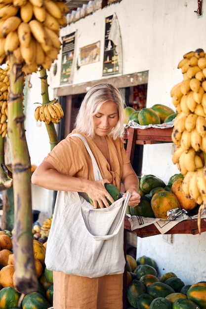 Frau kaufen frische Papaya am tropischen lokalen Markt