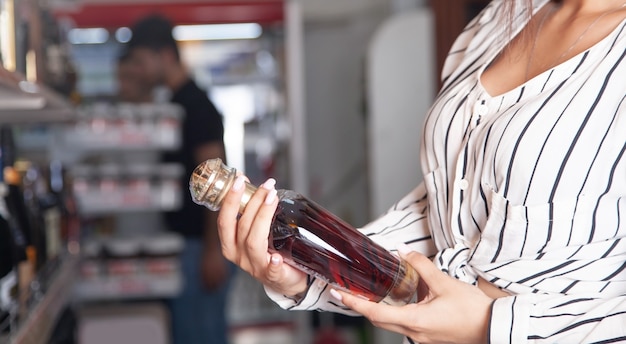 Frau kauft Cognac im Supermarkt.