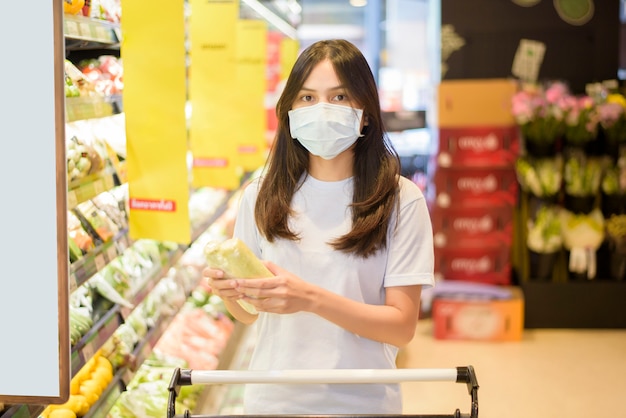 Frau kauft im Supermarkt mit Gesichtsmaske ein