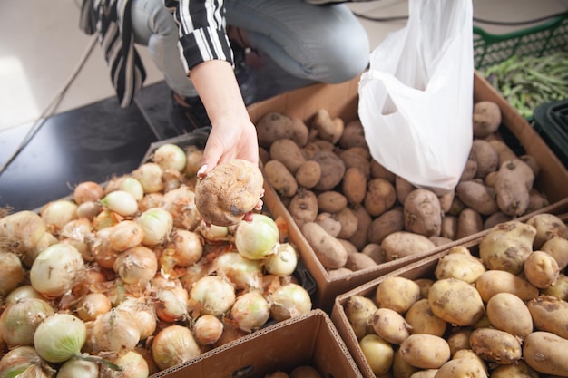 Frau kauft Kartoffeln im Lebensmittelgeschäft