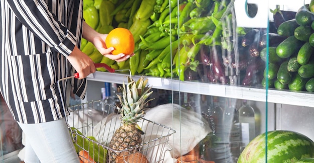 Frau kauft Orange im Lebensmittelgeschäft