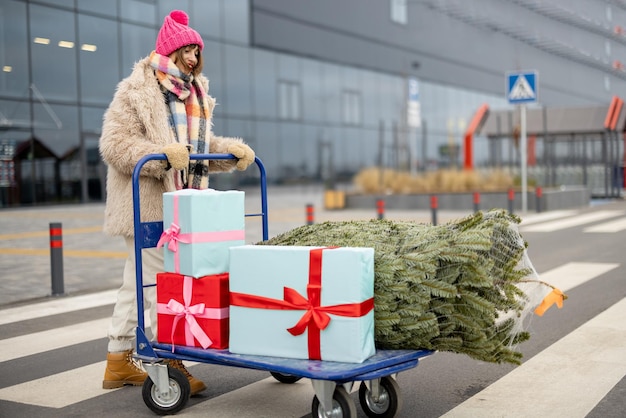 Frau kauft Weihnachtsbaum und Geschenke im Einkaufszentrum