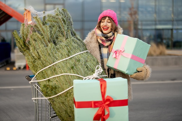 Frau kauft Weihnachtsbaum und Geschenke im Einkaufszentrum