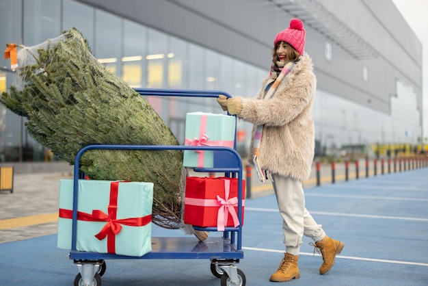 Frau kauft Weihnachtsbaum und Geschenke im Einkaufszentrum