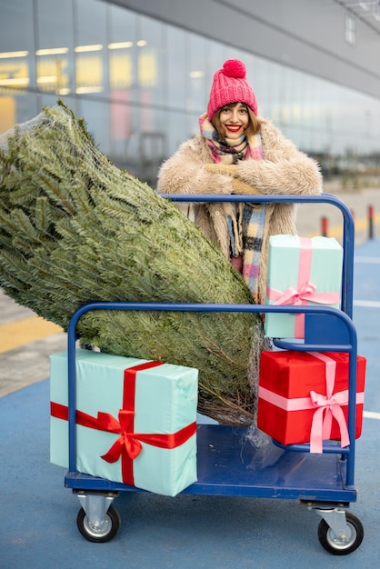 Frau kauft Weihnachtsbaum und Geschenke im Einkaufszentrum