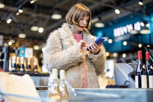 Frau kauft Wein im Supermarkt