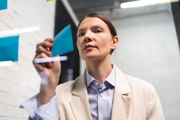 Frau klebt Post-it auf mittlerer Aufnahme des Fensters