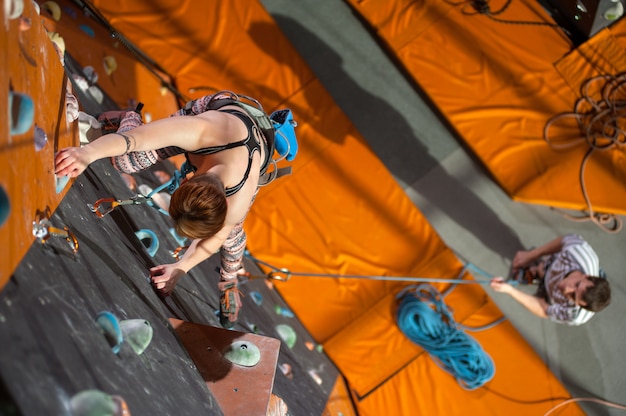 Frau klettert oben mit Karabiner und Seil