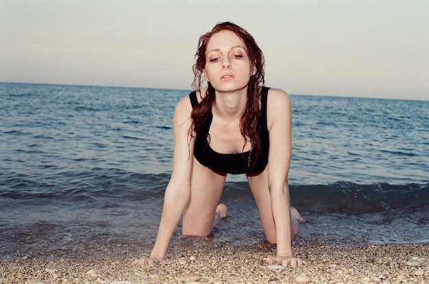 Foto frau kniet am strand vor klarem himmel