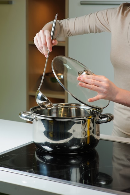 Frau kocht die Suppe in der Küche