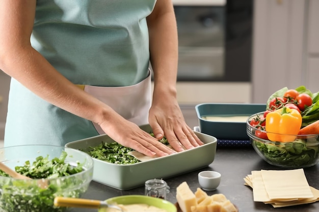 Frau kocht Spinatlasagne in der Küche