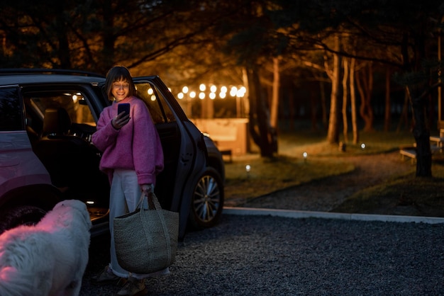 Frau kommt mit dem Auto zu einem Haus im Wald