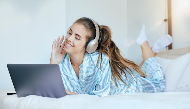 Frau Kopfhörer und entspannen Sie sich auf dem Laptop im Schlafzimmer, um Filme Online-Show und Medienunterhaltung zu Hause herunterzuladen Fröhliche junge weibliche Musik und Computer zum Streamen von Abonnement-Podcast und Audio