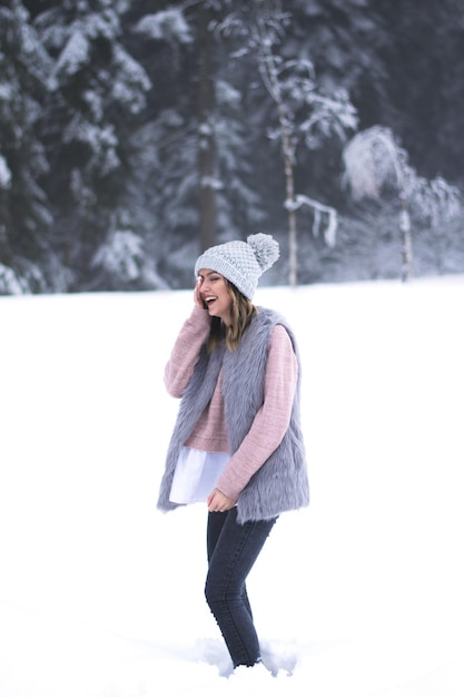 Frau lacht, während sie auf einem mit Schnee bedeckten Feld steht