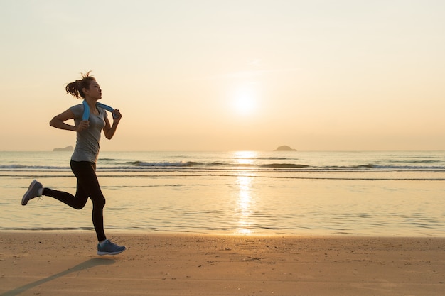 Frau läuft am strand bei sonnenaufgang