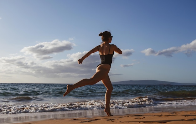 Frau läuft am Strand Junges gesundes Mädchen läuft am Sonnenaufgangstrand