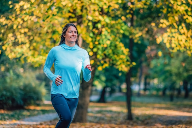 Frau läuft im Herbst im öffentlichen Park