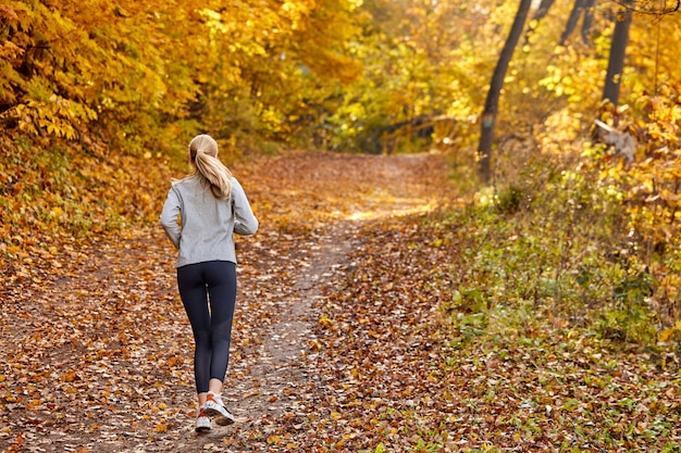 Frau läuft Joggen im Wald, Sportkleidung tragend